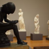 Statue of boy inspecting foot