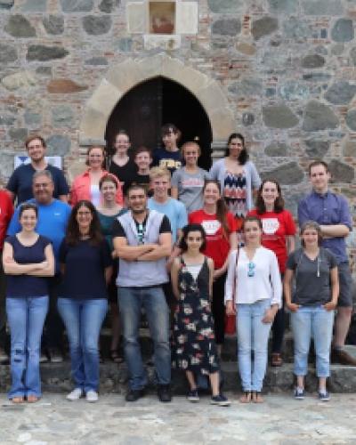 A group of students pose in front of the entrance to a stone building